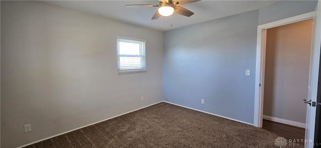 unfurnished room featuring baseboards, dark carpet, and a ceiling fan