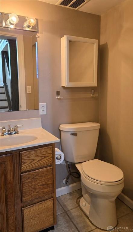 bathroom with tile patterned floors, toilet, vanity, baseboards, and visible vents