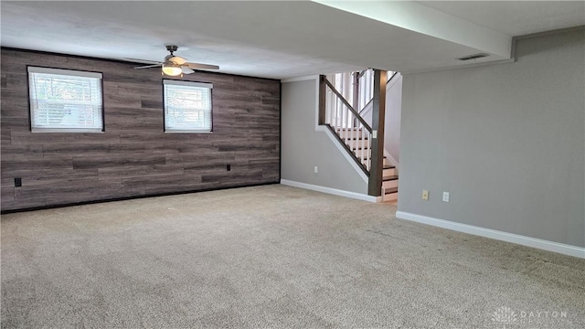 basement with carpet flooring, visible vents, wooden walls, baseboards, and stairs