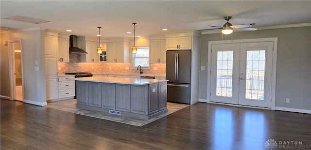 kitchen featuring white cabinetry, wall chimney exhaust hood, light countertops, and freestanding refrigerator