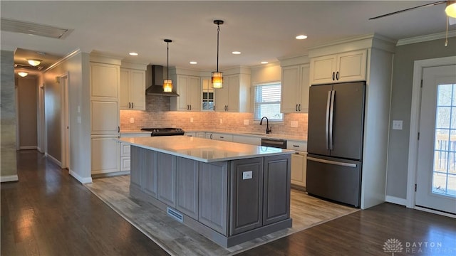 kitchen with wood finished floors, a sink, wall chimney range hood, black electric range, and freestanding refrigerator