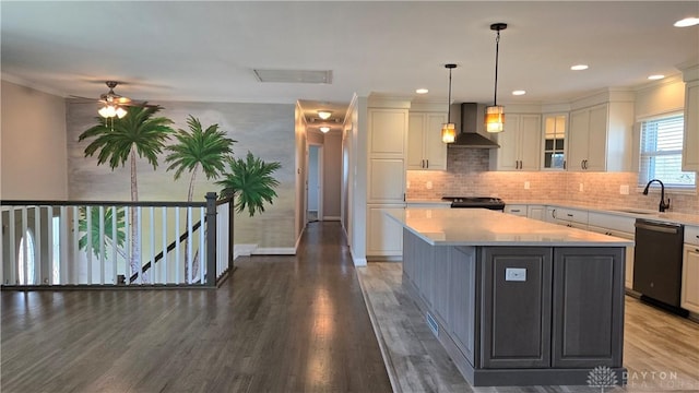 kitchen featuring a sink, light countertops, black appliances, and wall chimney exhaust hood