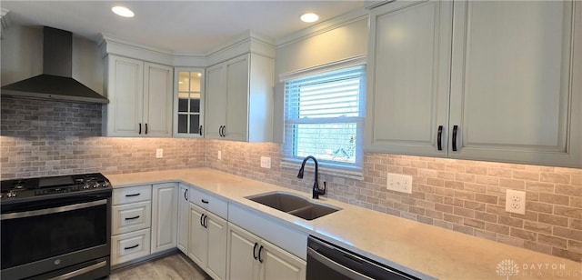 kitchen featuring light countertops, wall chimney exhaust hood, a sink, dishwashing machine, and gas range