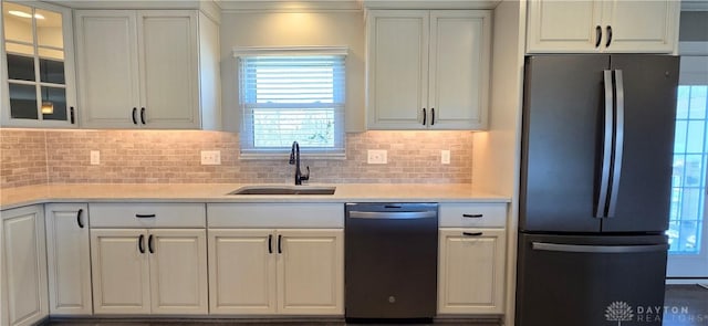 kitchen featuring light countertops, a sink, dishwashing machine, and freestanding refrigerator
