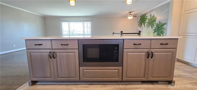 kitchen featuring black microwave, baseboards, crown molding, and light countertops