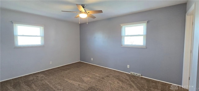 empty room with visible vents, dark colored carpet, and a ceiling fan