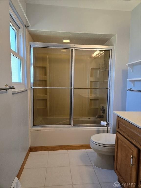 full bathroom with baseboards, toilet, tile patterned floors, vanity, and shower / bath combination with glass door