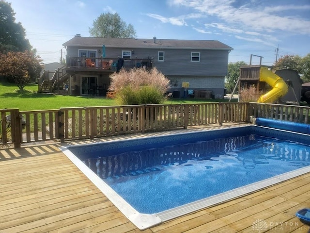 view of pool with a covered pool, a playground, stairway, a deck, and a yard