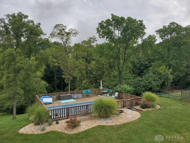 view of swimming pool featuring fence, a deck, an outdoor living space, a lawn, and a view of trees