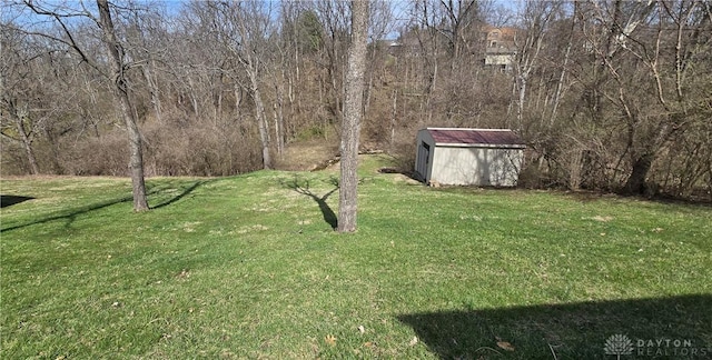 view of yard featuring an outdoor structure, a forest view, and a shed