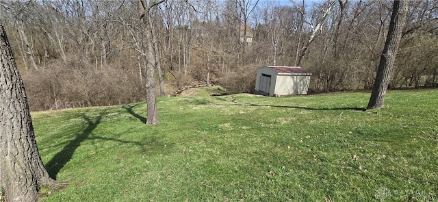 view of yard with an outdoor structure, a wooded view, and a shed