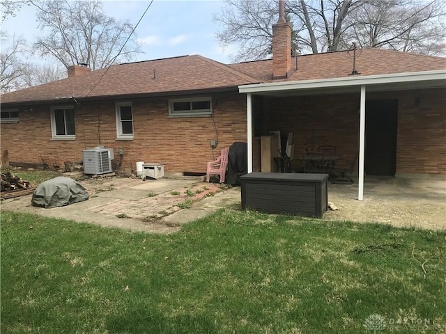 7581 Lockwood St, Dayton, OH 45415 - back of house featuring a chimney, a patio area, a lawn, a shingled roof, and brick siding
