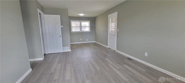 foyer with baseboards, visible vents, and wood finished floors