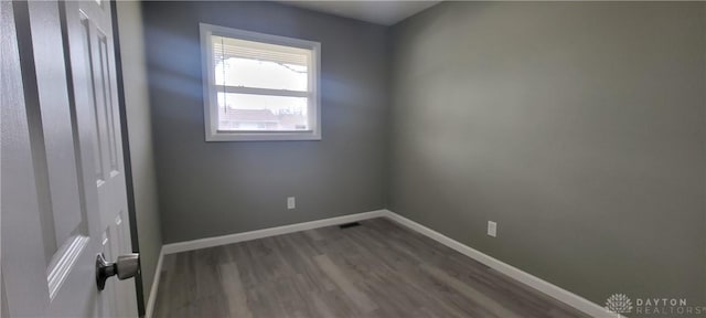 empty room featuring visible vents, baseboards, and wood finished floors