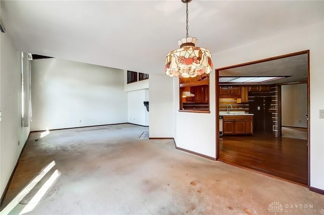 unfurnished living room featuring a sink, a notable chandelier, and baseboards
