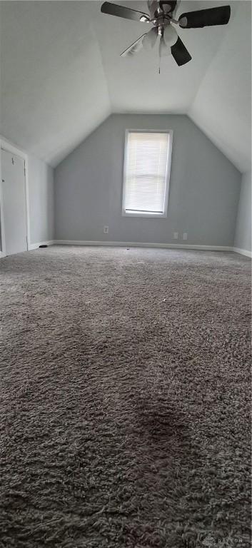 additional living space featuring carpet floors, baseboards, vaulted ceiling, and ceiling fan