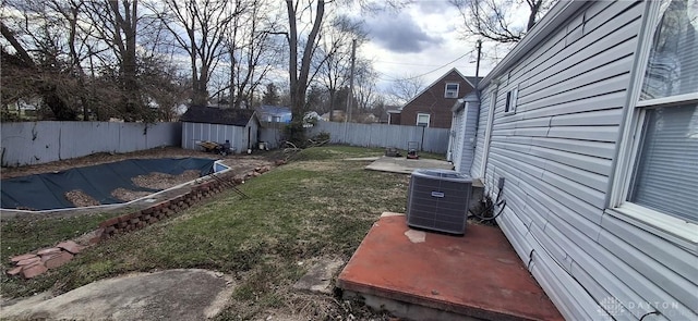 view of yard with central air condition unit, a fenced backyard, an outdoor structure, and a shed