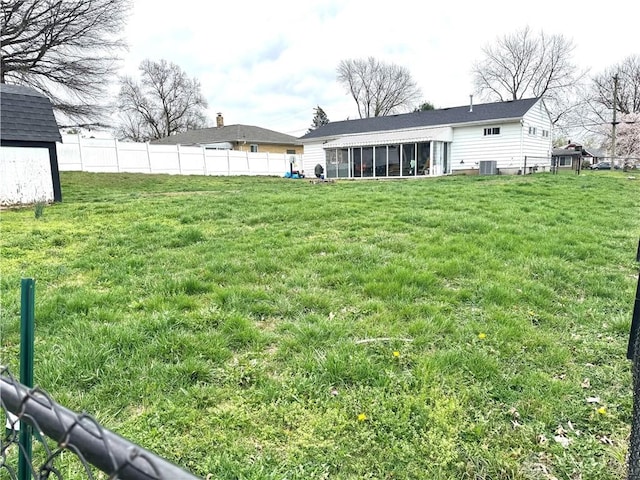 view of yard with central air condition unit, an outdoor structure, fence, a sunroom, and a storage unit