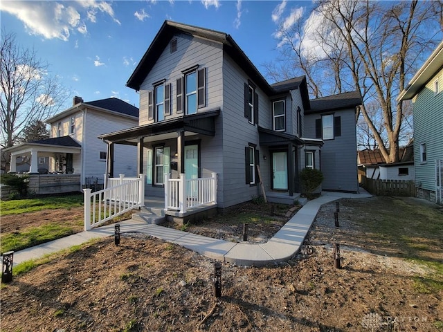 traditional-style home featuring covered porch and fence