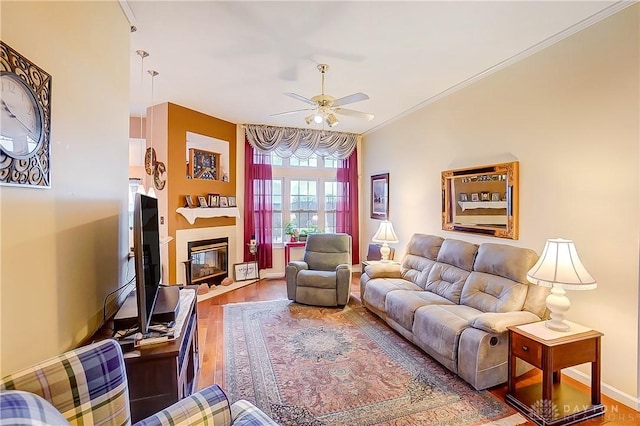 3949 E Summit Ridge Dr, Beavercreek, OH 45430 - living area featuring ceiling fan, wood finished floors, a glass covered fireplace, crown molding, and baseboards