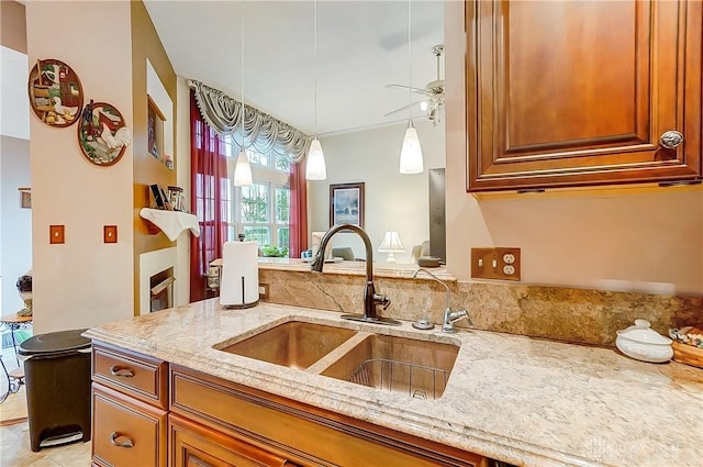 3949 E Summit Ridge Dr, Beavercreek, OH 45430 - kitchen featuring a sink, light stone countertops, a ceiling fan, and brown cabinetry