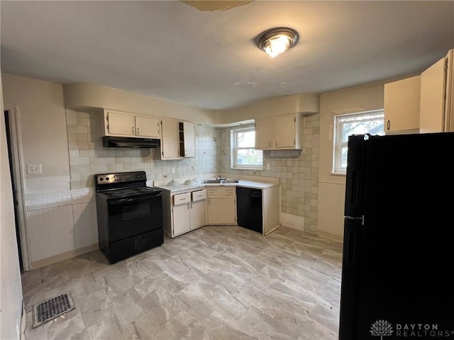 kitchen featuring light countertops, under cabinet range hood, a sink, visible vents, and black appliances