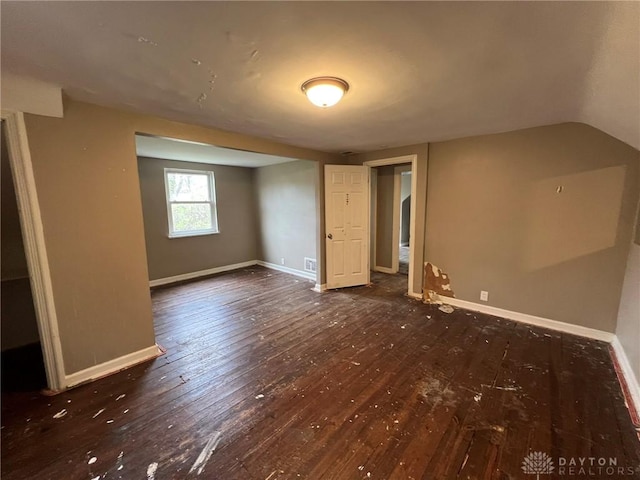 interior space featuring hardwood / wood-style floors, baseboards, and vaulted ceiling