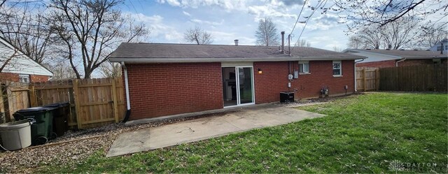back of house featuring a patio area, brick siding, a fenced backyard, a lawn, and roof with shingles