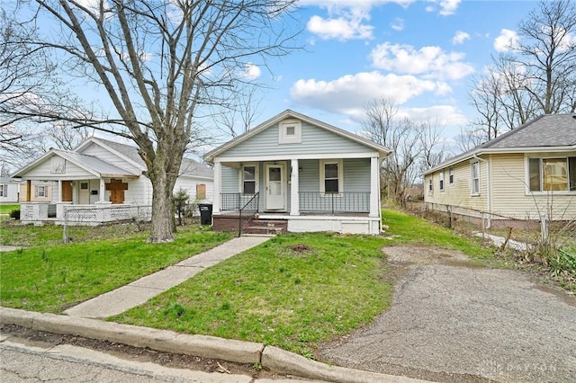 view of front of house with covered porch, fence, and a front lawn
