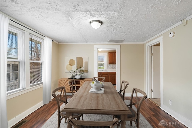 dining area with a textured ceiling, baseboards, visible vents, ornamental molding, and dark wood-style flooring