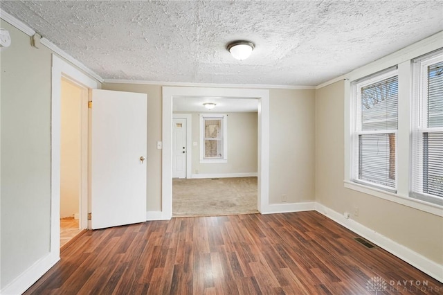 spare room with plenty of natural light, dark wood-type flooring, baseboards, a textured ceiling, and visible vents