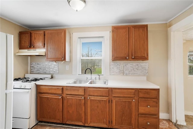 kitchen featuring light countertops, gas range gas stove, a sink, and under cabinet range hood