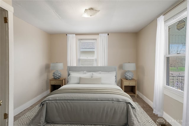 carpeted bedroom featuring multiple windows and baseboards