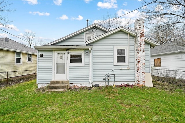 rear view of property with a yard, fence, a chimney, and entry steps