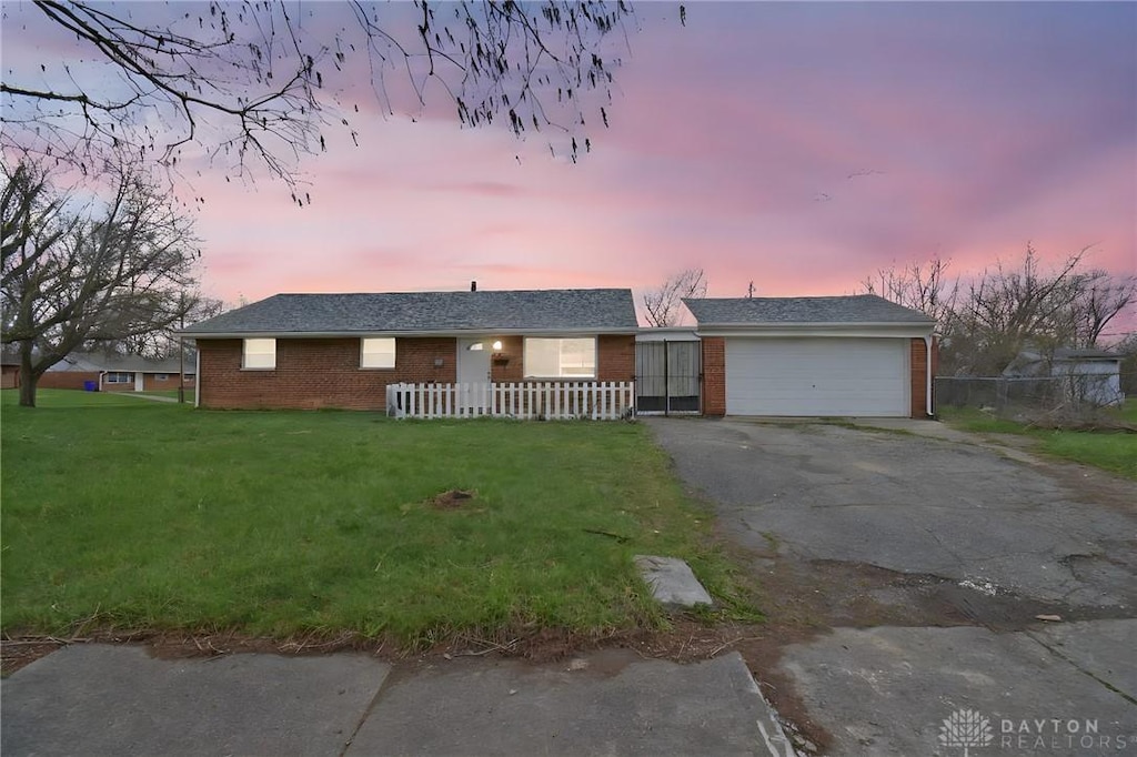 683 Tyson Ave, Dayton, OH 45417 - single story home featuring driveway, fence, brick siding, a lawn, and a garage