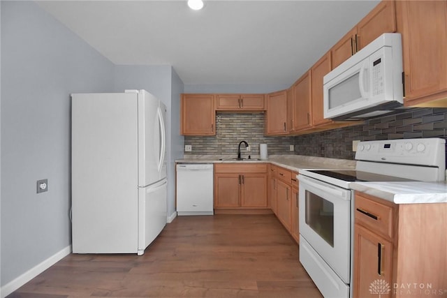 kitchen featuring light countertops, a sink, backsplash, and white appliances