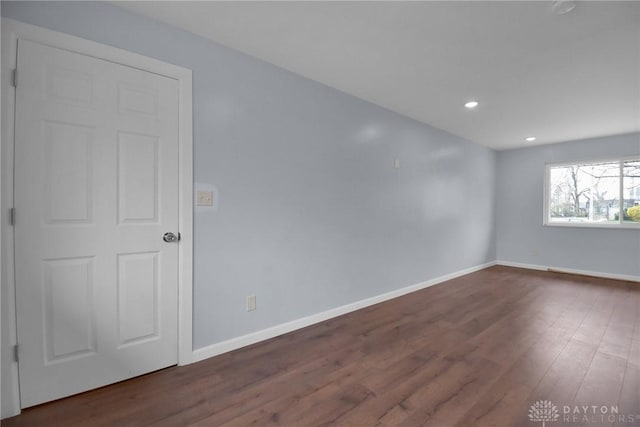 spare room with baseboards, dark wood-style flooring, and recessed lighting