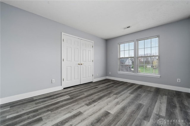 unfurnished bedroom with baseboards, visible vents, and wood finished floors