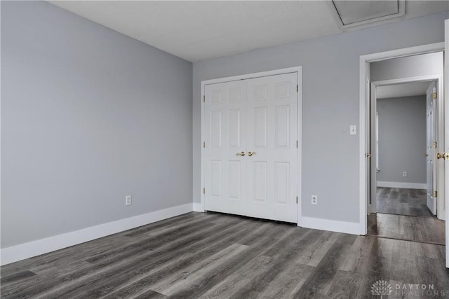unfurnished bedroom with baseboards, wood finished floors, and a closet