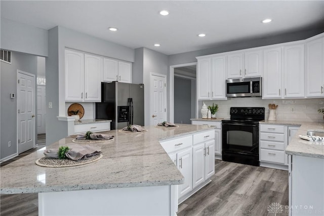 kitchen featuring a kitchen island, light wood-type flooring, stainless steel microwave, black electric range, and fridge with ice dispenser