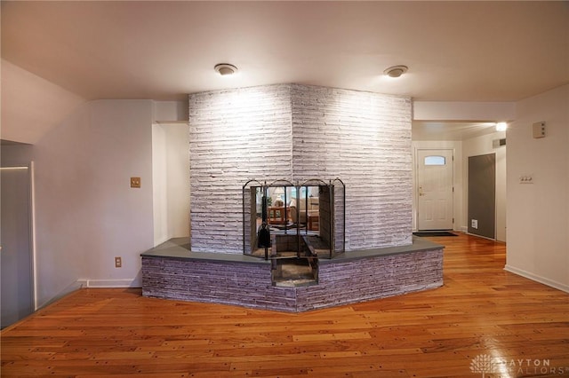 5566 Mad River Rd, Dayton, OH 45459 - unfurnished living room with a multi sided fireplace, baseboards, and wood finished floors