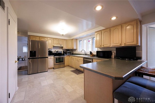 5566 Mad River Rd, Dayton, OH 45459 - kitchen featuring appliances with stainless steel finishes, dark countertops, a sink, a peninsula, and under cabinet range hood