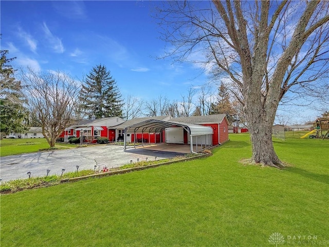 view of yard with driveway, a detached carport, and a playground