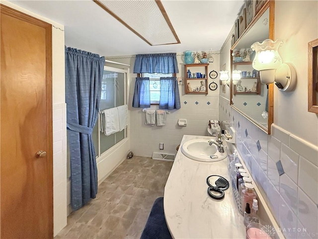 full bath with tile walls, visible vents, enclosed tub / shower combo, and vanity