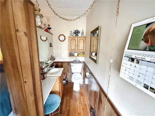 half bathroom featuring wood finished floors, toilet, and vanity
