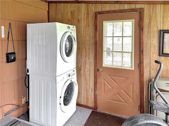 clothes washing area with stacked washing maching and dryer and laundry area