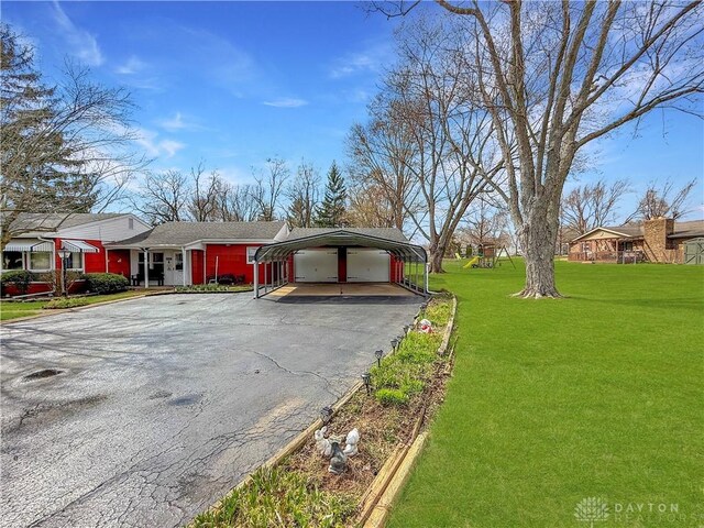 exterior space with aphalt driveway, a detached carport, and a front lawn