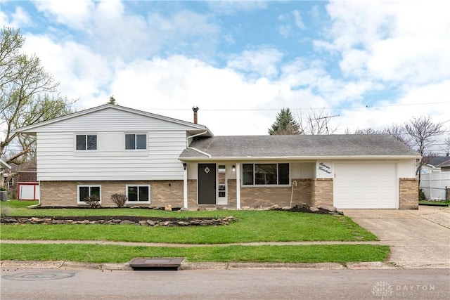 split level home featuring driveway, a front yard, an attached garage, and brick siding