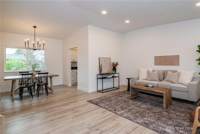 living room with an inviting chandelier, recessed lighting, baseboards, and light wood-type flooring