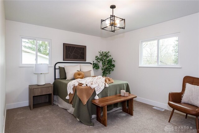 bedroom with light carpet, baseboards, and a chandelier